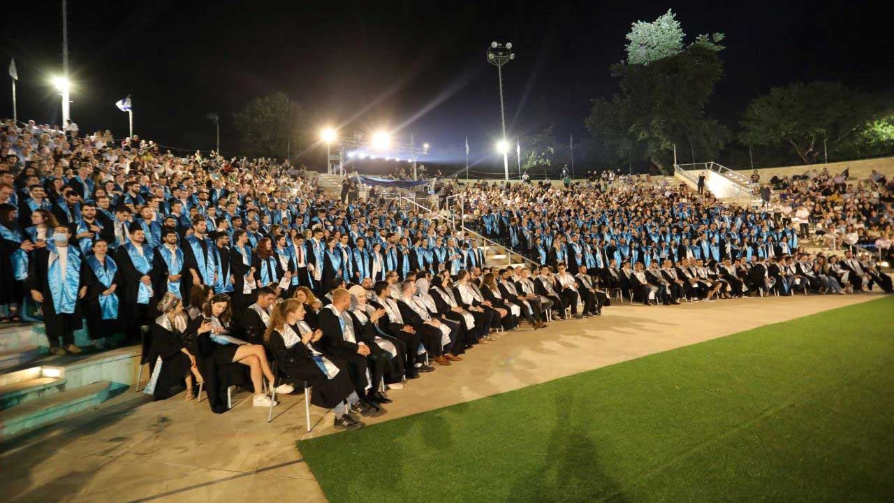 Graduates in gowns at an evening Bar-Ilan degree ceremony